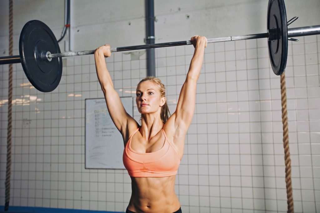 Fit young female athlete lifting heavy weights